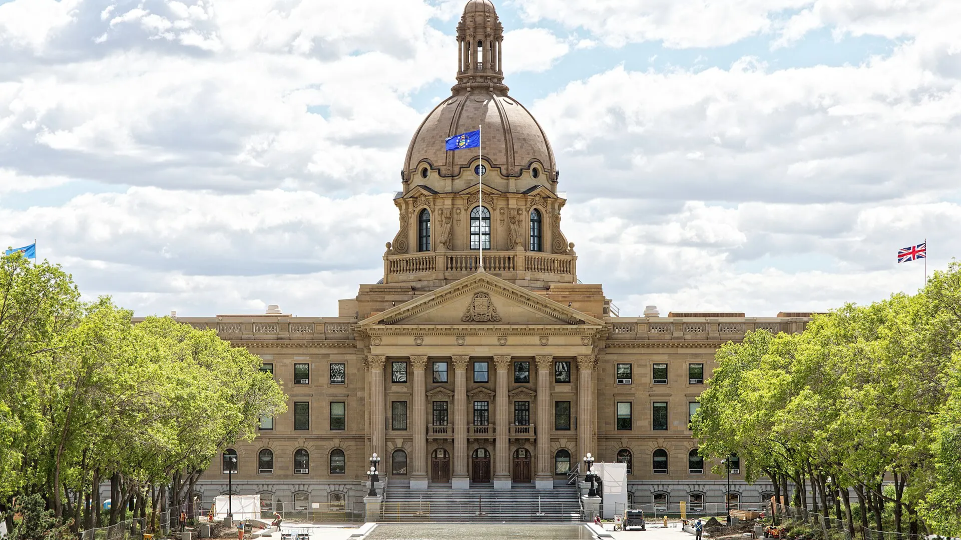 The domed sandstone Alberta Legislature Building in Edmonton seen from its grounds on a clear day in June 2024