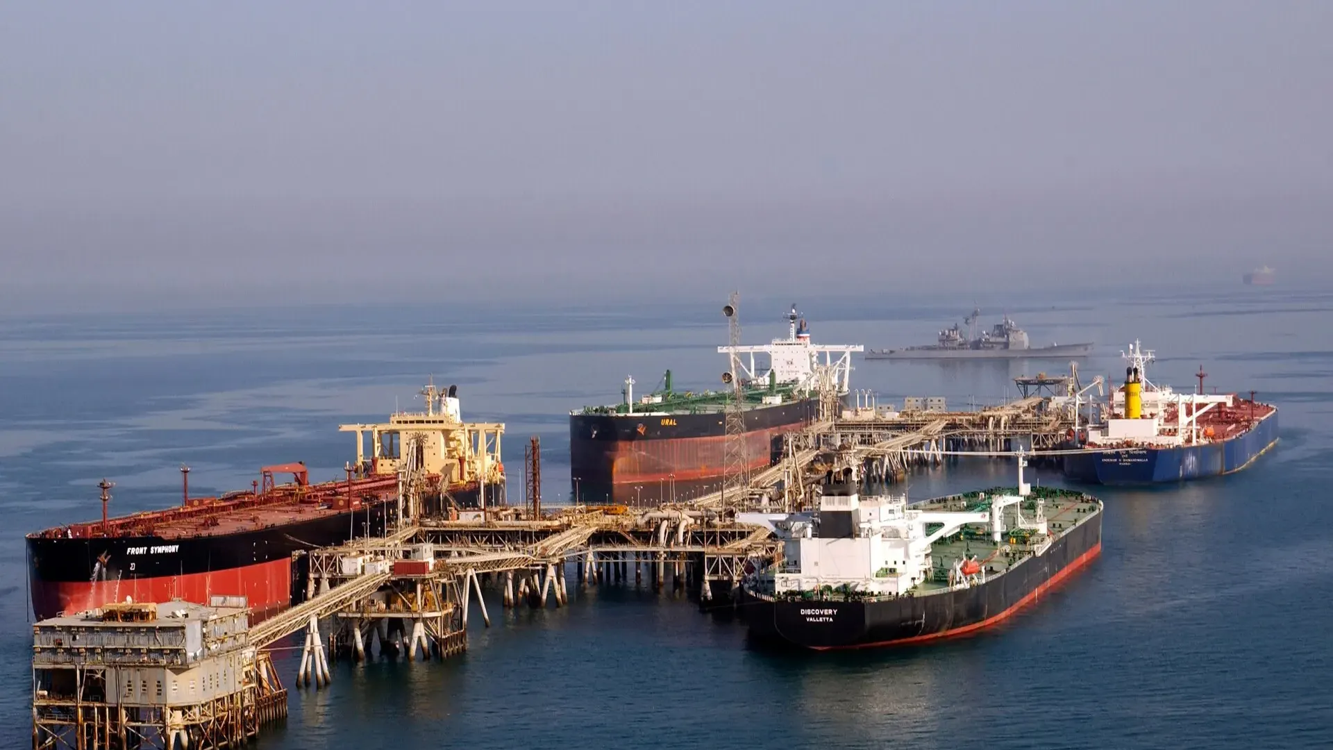 Four crude oil tankers moored at the offshore Al Basra Oil Terminal in the northern Gulf, with a US Navy cruiser in the distance
