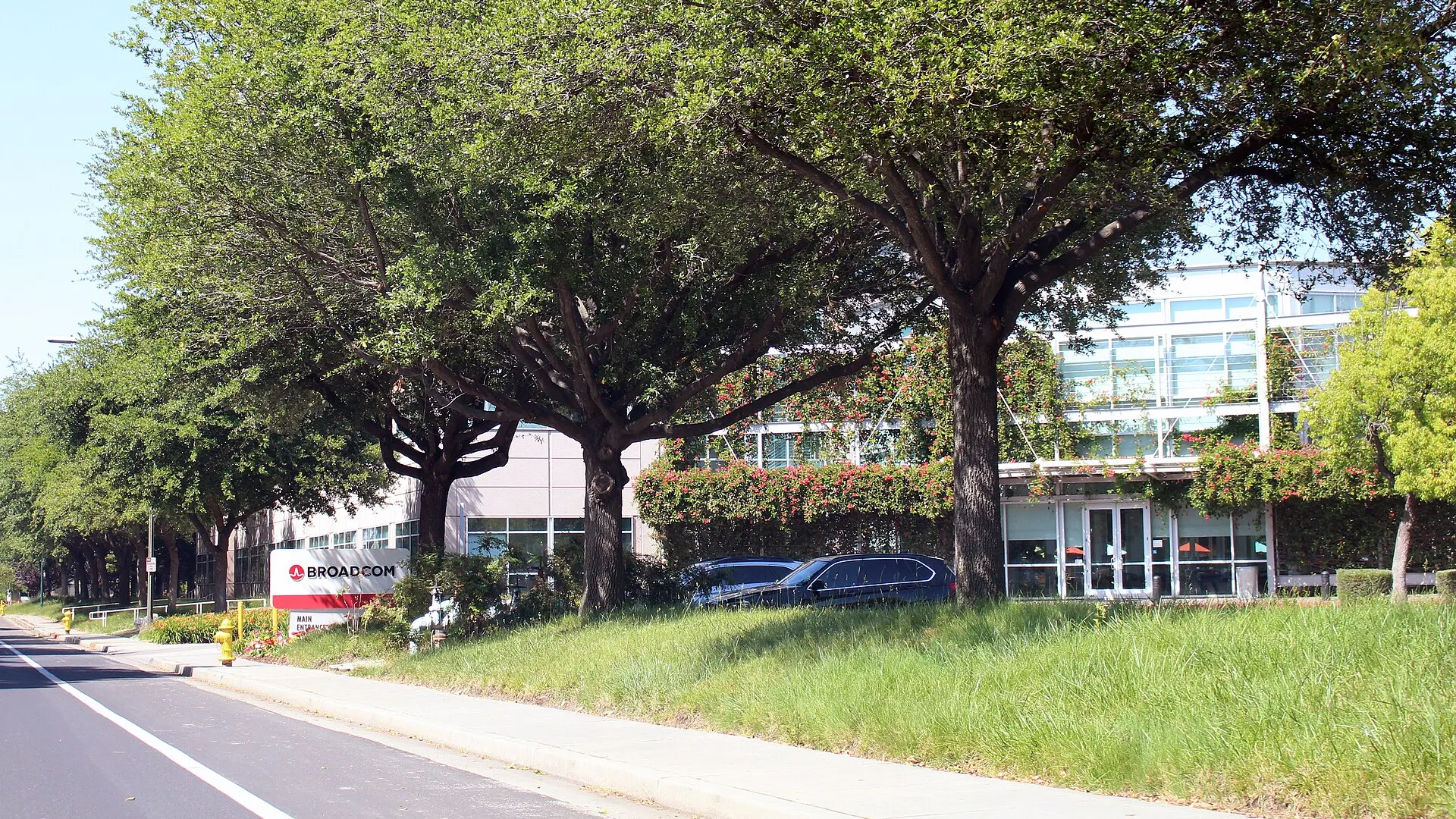 The low glass and concrete Broadcom Inc. headquarters building in San Jose, California, seen from the street on a clear day