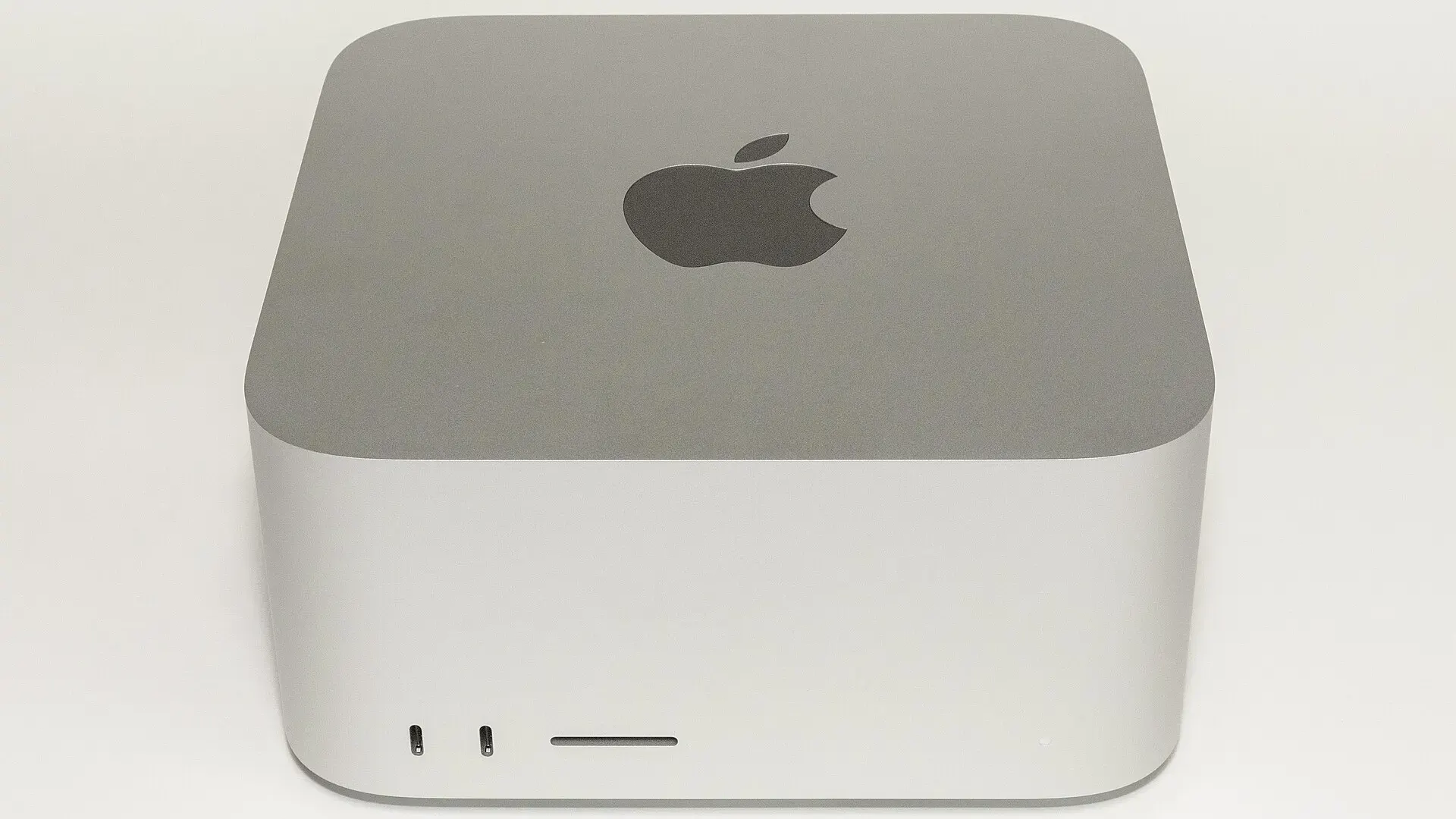 A silver Apple Mac Studio desktop computer photographed from the front against a plain white background, showing two ports and a card slot