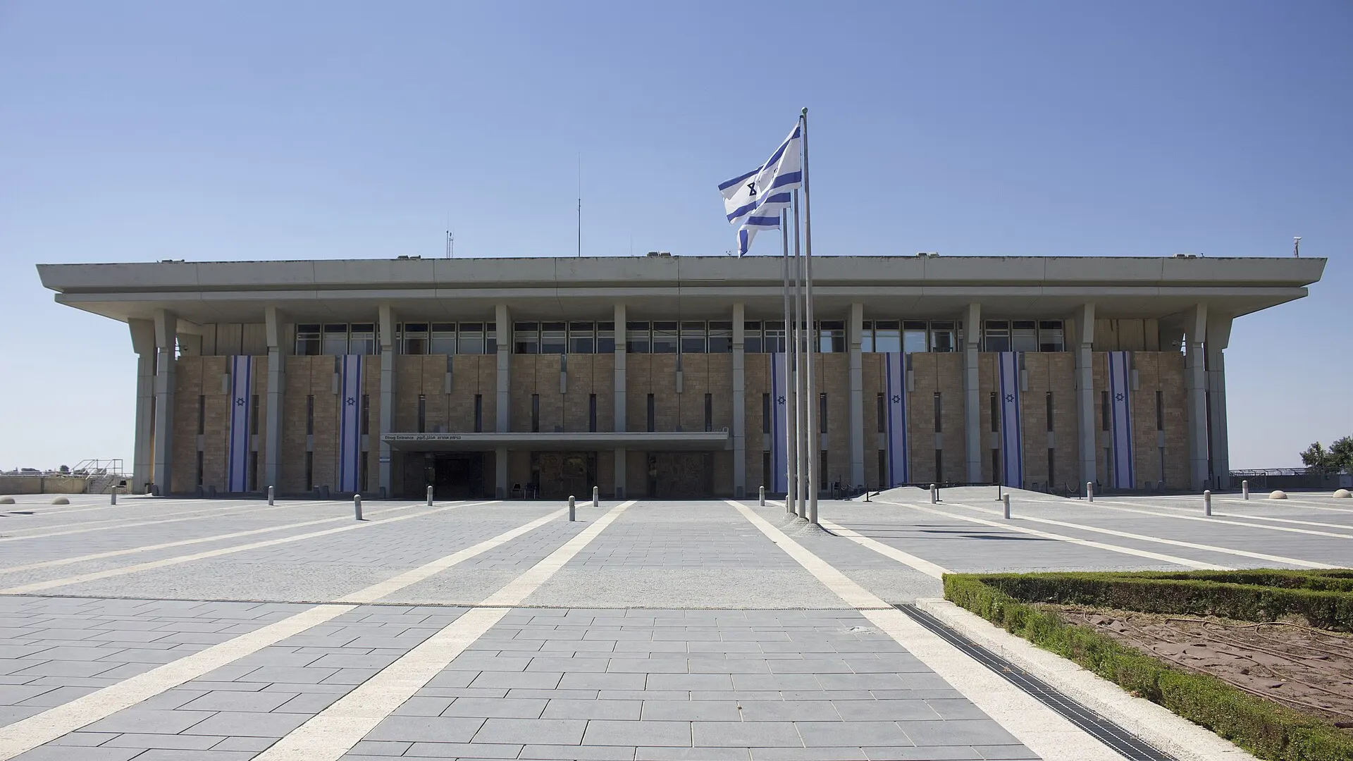 The Knesset parliament building in Jerusalem seen from the front, with its colonnaded facade and open plaza under clear sky