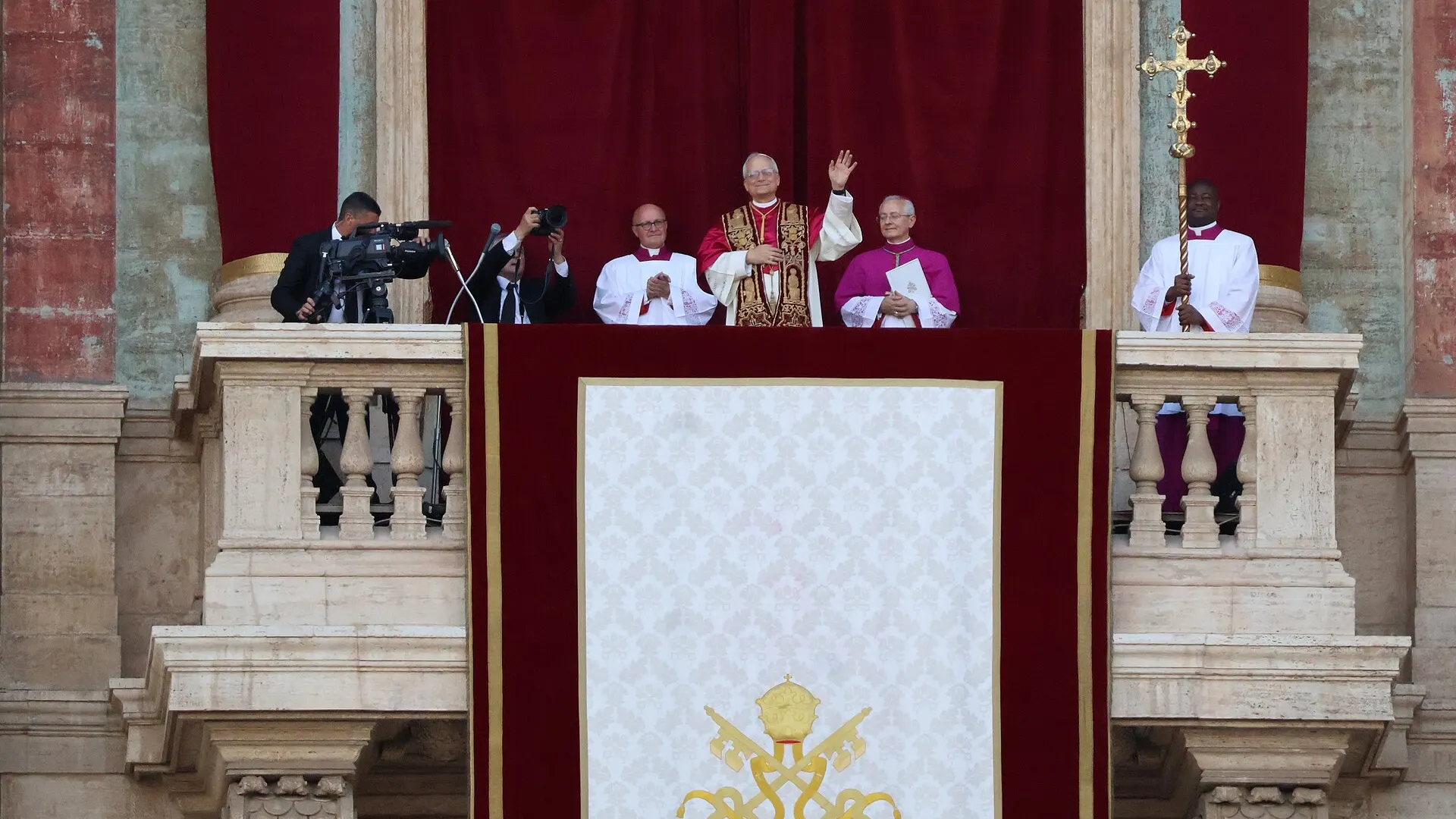 Pope Leo XIV in white vestments with arms raised on the central loggia of St Peter's Basilica after his election in Vatican City