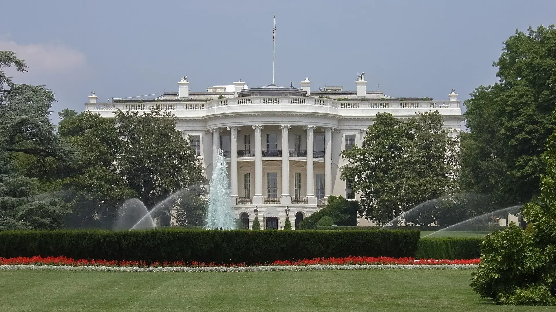 The White House in Washington, D.C., seen across its lawn and fountain under a clear sky in July 2007