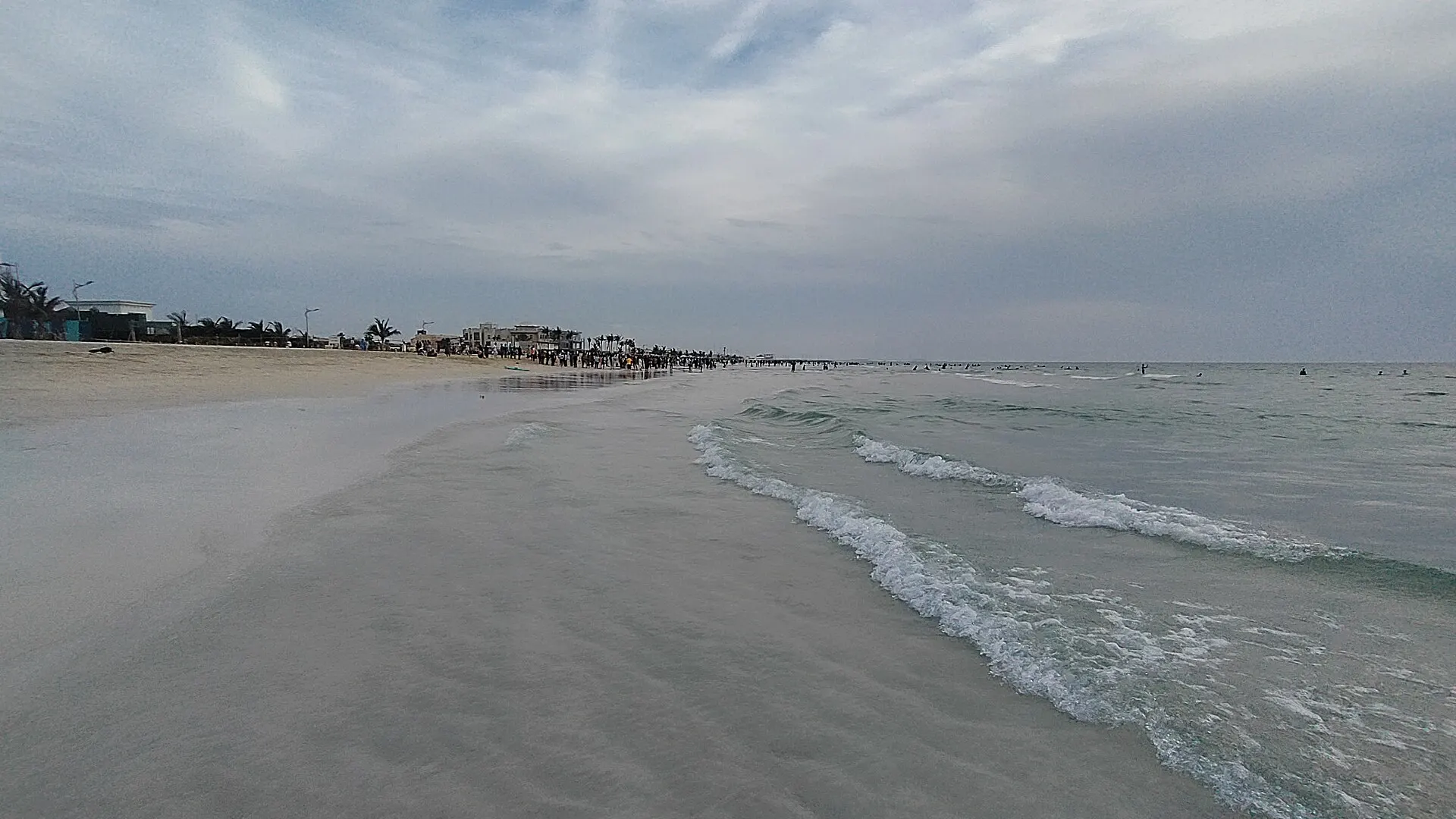 The sandy shore of an Umm Al Quwain beach at sunset, with fine sand and calm, clear water along the coast